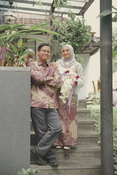 Andrika dan Aliva berdiri di tangga depan rumah, Aliva membawa buketnya.